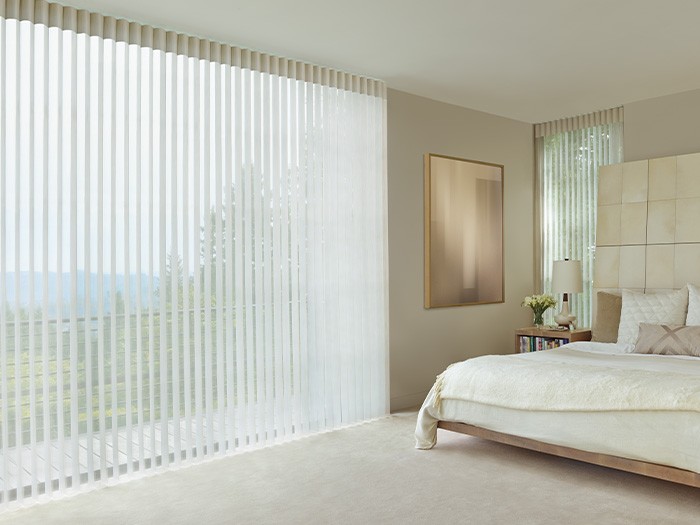 Une chambre à coucher avec de grandes fenêtres équipées de voilages Luminette®; tissu : Terra; couleur : riz blanc